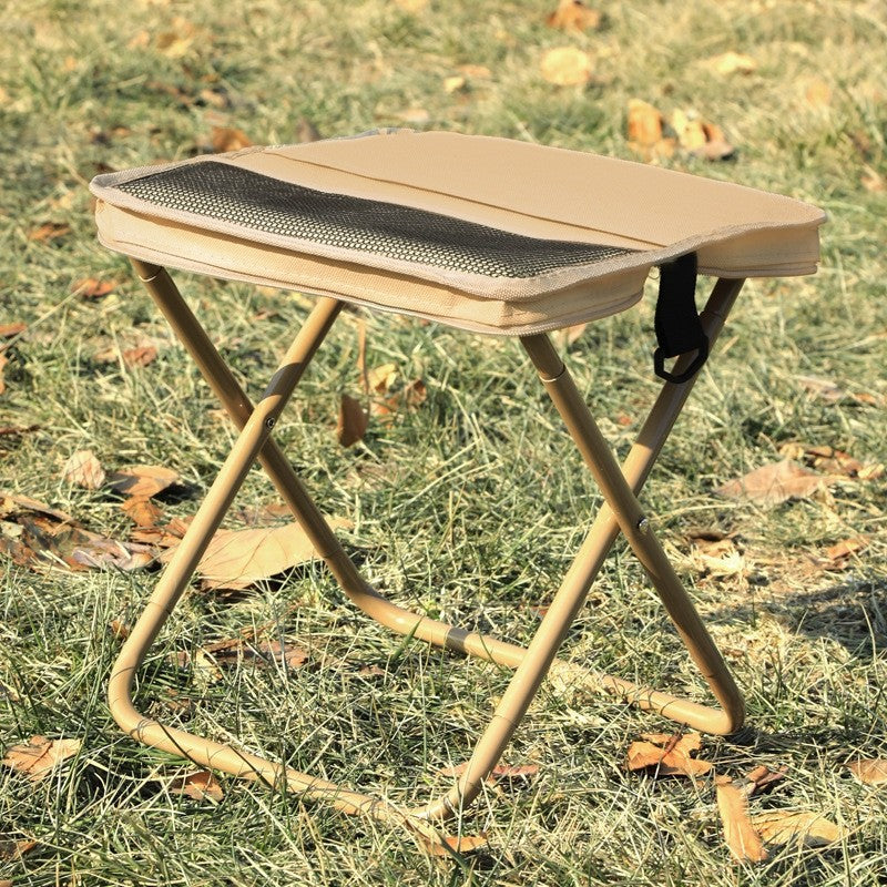 Foldable stool with a cushioned seat on a grassy ground